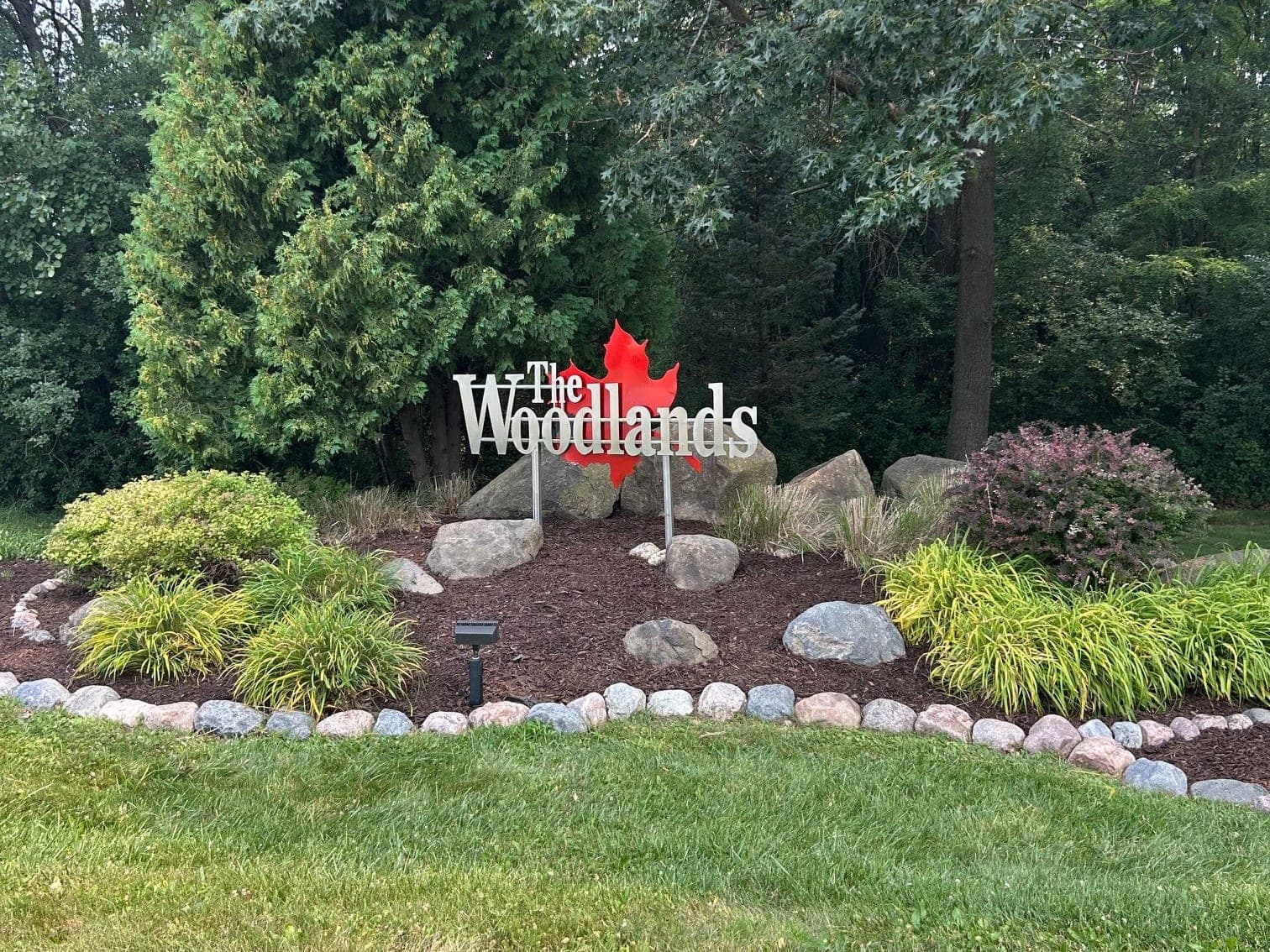 Fresh mulch bed with boulders at a neighborhood entrance sign