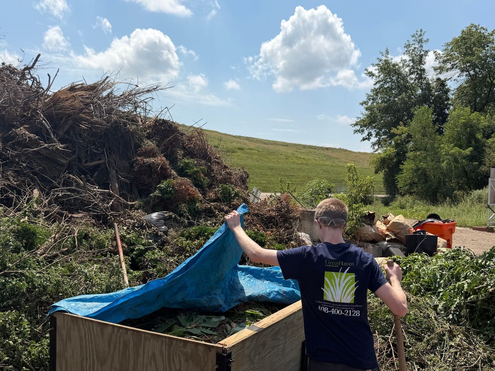 Crew member tarping a trailer full of brush after a cleanup